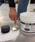 Applying Heavy Duty Silicone Roof Patch Kit 2 Gallon Black with a brush on a surface for waterproofing.