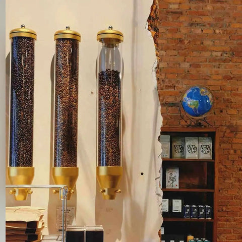 No Fuss Wall Mounted Coffee Bean Dispenser Set, Airtight Clear Window Jars With Easy Pour Valves, Sweet Kitchen Setup For Busy Home Bars And Local Cafes, Sleek Gold Finish 4 Pack on wall with coffee beans visible.
