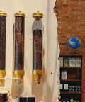 Wall Mounted Coffee Bean Dispenser Set with three round sealed acrylic jars for bulk beans in a cafe setting.