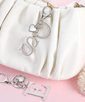 Custom Initial V Keychain In Stainless Steel Key Ring Silver Alphabet Charm For Women And Men shown with purse and accessories.