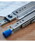 High Octane Heavy Duty Side Mount Ball Bearing Drawer Slides With Triple Extension Full Reach Cold Rolled Steel Cabinet Rails close up view on a wooden table.