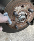Close-up of wheel hub with hand inserting a lug bolt, part of 10Pcs M12x1.5 Wheel Studs 43mm Lug Bolts For Honda Accord Civic CRV CRX.