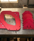 Professional Grade Built Tough Router Corner Template Jig With Interchangeable Curvature Plates and Red Anodized Aluminum Frame displayed on a workbench.