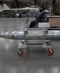 Museum display of a military aircraft and a missile on a trolley in a hangar