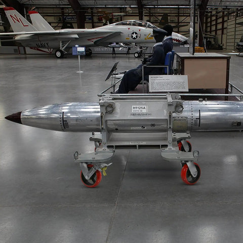 Museum display of a military aircraft and a missile on a trolley in a hangar
