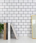 Thick Peel And Stick Backsplash Tiles In White Subway Style For Kitchen 10 Sheets Of 12 By 12 Inches 2mm To 2.5mm Thick Durable Self Adhesive DIY Friendly Easy Install Covers 40 Percent More Area shown on a wall with books and a plant.