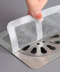 A hand placing a silver mesh hair catcher over a sink drain, part of a 20 Pack Disposable Shower And Kitchen Drain Hair Catchers Keep Your Pipes Snatched With Dope Anti Clog Mesh Guards That Straight Up Block Grease And Gunk Everyday.