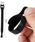 Hand holding 15cm reusable cable tie, black nylon, shown next to size diagram. 100 Pack Reusable Cable Ties And Straps, 6 Inch By 0.47 Inch Thin Cord Organizers With Hook And Loop For Quick Home Office And Data Centers, Black