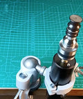 Close-up of the Rock Solid Workhorse Electric Leather Burnisher And Bench Polish Machine featuring the dual voltage clamp design on a green cutting mat.