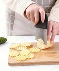 Front view: stainless steel crinkle cutter with ergonomic black non-slip handle slicing ridged potatoes on cutting board