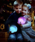 Two children holding glowing moon lamps in a cozy room during festive holidays.