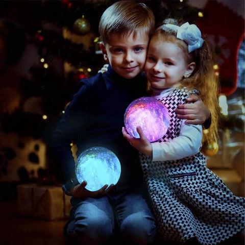 Two children holding glowing moon lamps in a cozy room during festive holidays.