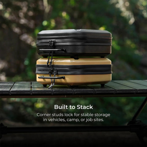Stacked Nestout Gear Storage Cases in black and beige, on outdoor table, showcasing lightweight hard shell and impact resistance.