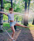 Person balancing on 60 Feet Slackline Kit With Tree Guards, Carry Bag, And Easy Setup for Family Fun in a park