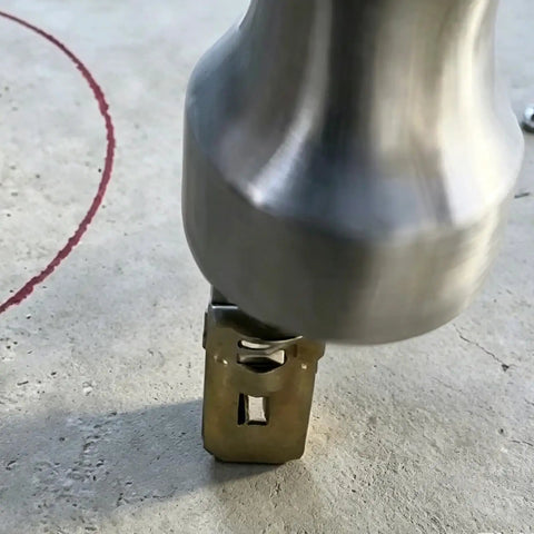 Close-up of a metal tool pressing into a surface with marked red circle, not related to Self Drilling Drywall Anchors and Screws Kit image