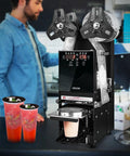 No Fuss Fully Automatic Cup Sealer Pumping Six Hundred Cups Hour With Digital Control Panel sealing cups in a coffee bar.