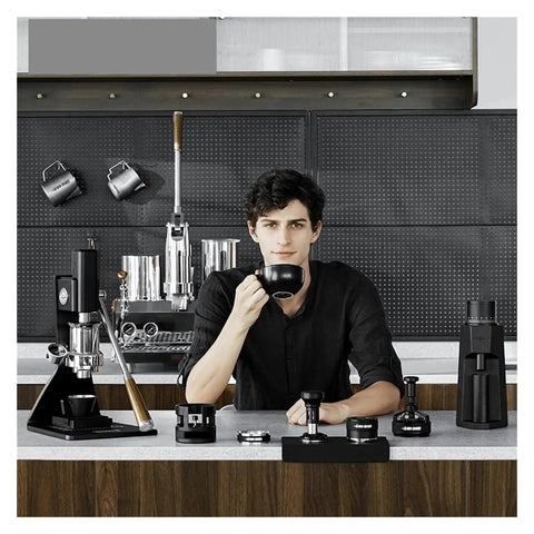 Level Up Your Home Barista Setup With This Dope 58Mm Espresso WDT Tool Featuring Six Heat Resistant Needles Adjustable Depth Control And Hidden Magnetic Storage For Zero Fuss Morning Routines, showing a barista holding a black cup.