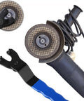 Hardcore Adjustable Pin Spanner Wrench For Angle Grinders With Rock Solid Handle And Sweat Free Disc Swap Kit Forged From Premium Chisel Tool Steel Measuring Seven Point Two Five Inches In Bold Blue next to an angle grinder.
