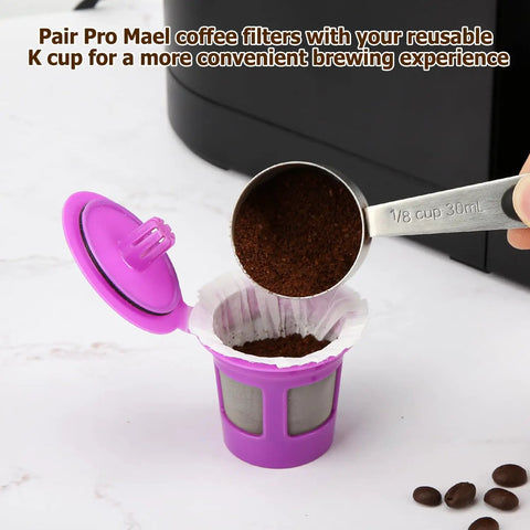 Scooping coffee into purple reusable K cup with 360 Count Disposable K Cup Filters For Keurig 1.0 And 2.0 Single Serve Brewers White Coffee Filter Paper For Use With Reusable K Cup Pods Premium German Paper in a coffee brewer setting.