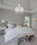Lit White Crystal Chandelier With Six Lights For Bedroom And Dining Room Modern Elegant Candle Ceiling Light Fixture Living Room Entryway Foyer Decor Sparkling K5 Drops And Glass Center Tray hanging above a bed in a bedroom.