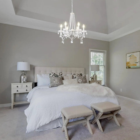 Lit White Crystal Chandelier With Six Lights For Bedroom And Dining Room Modern Elegant Candle Ceiling Light Fixture Living Room Entryway Foyer Decor Sparkling K5 Drops And Glass Center Tray hanging above a bed in a bedroom.