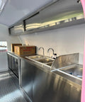 Interior view of the custom mobile coffee and pastry trailer featuring a stainless steel sink and counters. Kickstart Your Street Vending Hustle With This Custom Mobile Coffee And Pastry Trailer Towable Commercial Kitchen Equipped With A Fridge Griddle Sink Perfect For Catering Pros Ready To Roll.