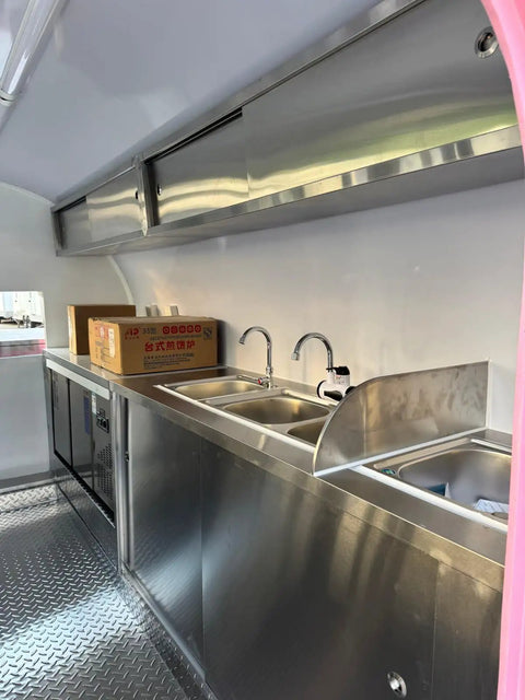 Interior view of the custom mobile coffee and pastry trailer featuring a stainless steel sink and counters. Kickstart Your Street Vending Hustle With This Custom Mobile Coffee And Pastry Trailer Towable Commercial Kitchen Equipped With A Fridge Griddle Sink Perfect For Catering Pros Ready To Roll.