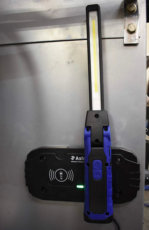 Double-Sided Folding LED Work Light with 1000 Lumen Flood hanging on a vertical surface showing wireless charging pad.
