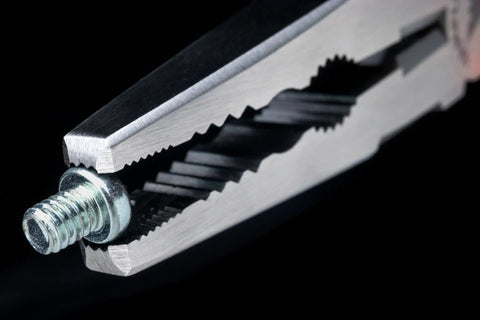Close-up of Caiman 7.5 Inch Stripped Screw Extractor Needle Nose Pliers With Wire Cutter Crimper holding a screw, made in Japan