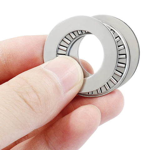 Close-up of two NTA1220 thrust needle roller bearings with washers, 1.25 in OD, steel.