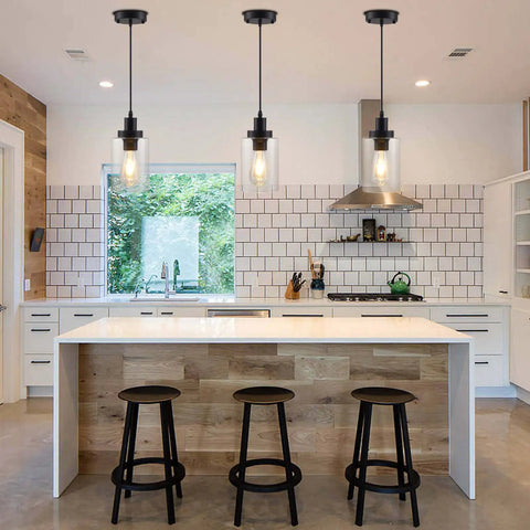 Three Pack Black Industrial Pendant Lights With Clear Glass Shades hanging over a modern kitchen island with wooden stools.