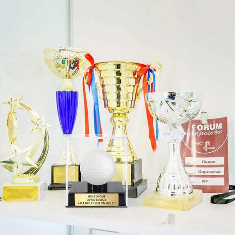Custom Golf Ball Display Case With Clear Acrylic Holder Laser Engraved Plaque on shelf with gold and silver trophies