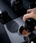 Straight Up Pro Grade 58Mm Espresso Accessories Kit with black aluminum tamper pressing coffee grounds in a portafilter.