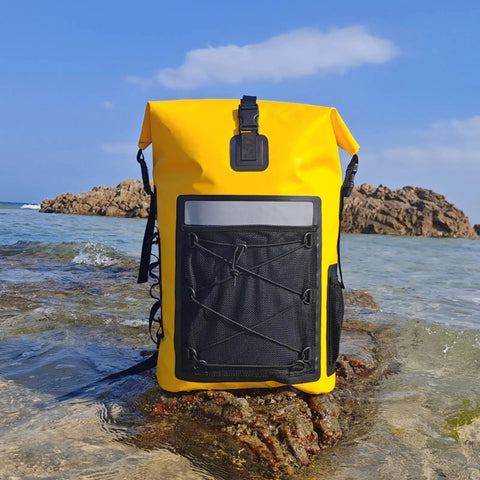 Yellow waterproof roll-top backpack with padded straps 35L daypack for hiking and camping on a rocky shore