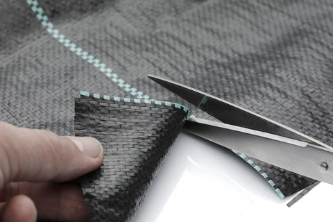Close-up of Heavy Duty Woven Weed Control Fabric 6 by 33 Feet Black Ground Cover Membrane being cut with scissors