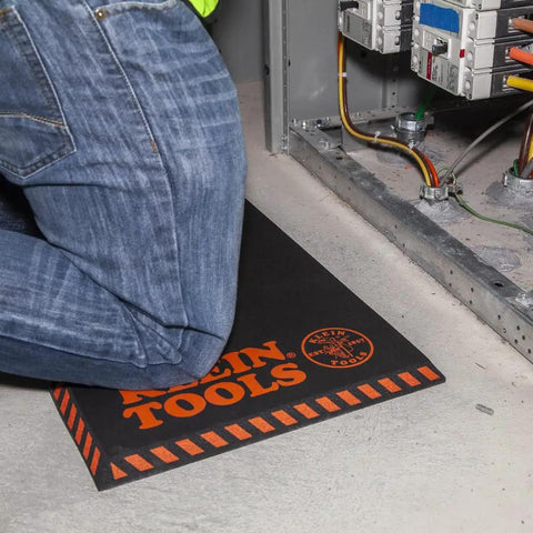 Tradesperson kneeling on Heavy Duty Kneeling Pad For Trades Pros With Handy Handle Large Soft Thick Closed Cell Foam Knee Cushion 1 Inch NBR Foam For All Day Comfort And Long Lasting Protection On Worksites.