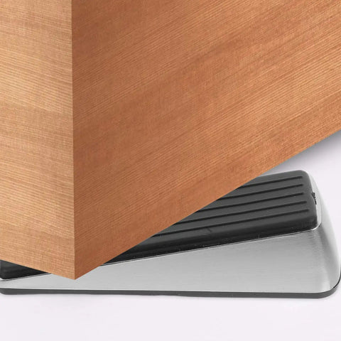 Heavy Duty Door Stop Wedge Stopper 2-Pack For Home, Office, And Apartment Safety Built Tough With Zinc Alloy And Rubber under a wooden door.