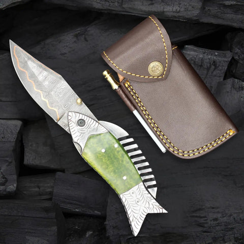 Fish Style Copper Damascus Folding Knife With Ladder Pattern Blade, Brass Engraved Handle, Leather Sheath displayed on black wood