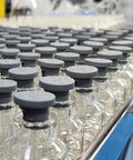 Glass vials with grey rubber stoppers on a production line