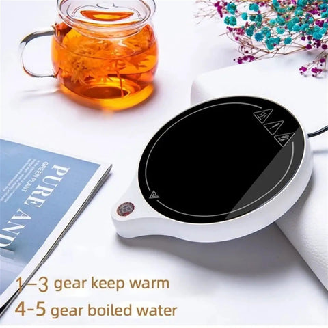 Solid Pick Mug Warmer And 200W Cup Heater That Keeps Your Daily Grind Steaming Hot Up To 100C With Five Precise Temperature Levels Plus Non Slip Base For Desk placed next to a glass tea pot and book.
