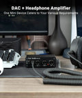 Q4 DAC Headphone Amp For PC And Home Audio Setup With USB Optical Coaxial Inputs, 3.5mm Headphone Output And RCA Speaker Outputs, Plug And Play Desktop Digital To Analog Converter For Richer Music, Gaming, And Movies. black metal DAC on desk with headphones