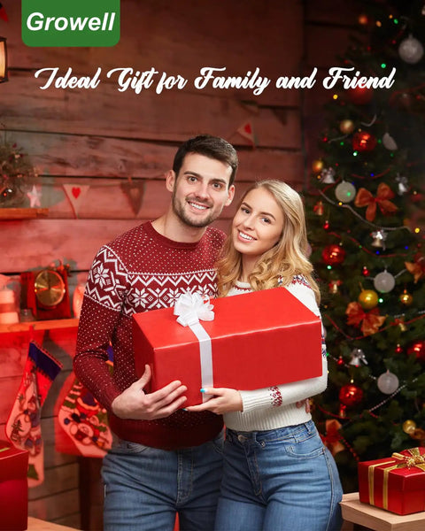 Couple holding a red gift box beside a Christmas tree, wearing festive sweaters, with decorated room in the background.