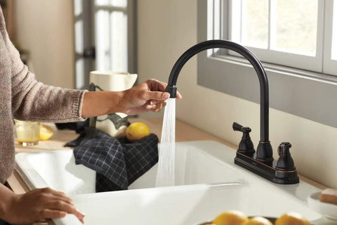 Person using Elmhurst Two-Handle Kitchen Faucet With Twist Aerator, Deck Mount, Oil Rubbed Bronze, High Arc Gooseneck Spout