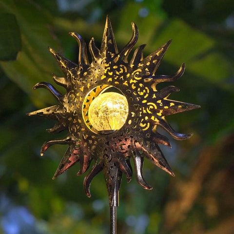Sun Powered Solar Garden Light Stake With Crackle Glass Metal Finish lit at night with glowing LED in garden setting.