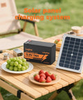 12V 7Ah LiFePO4 Battery for Ride On Toys and Outdoor Power next to solar panel on picnic table