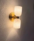 GLEAMING NEST Modern Alabaster Wall Sconce, Double Light Fixture, Antique Brass Finish, Fluted Stone Shades, Contemporary Wall Lamp viewed from the side.