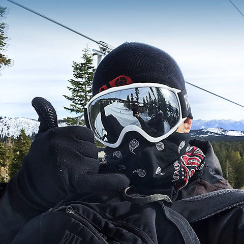 Findway OTG ski goggles with white frame and mirrored lens worn on a snowy slope by a skier in a black beanie