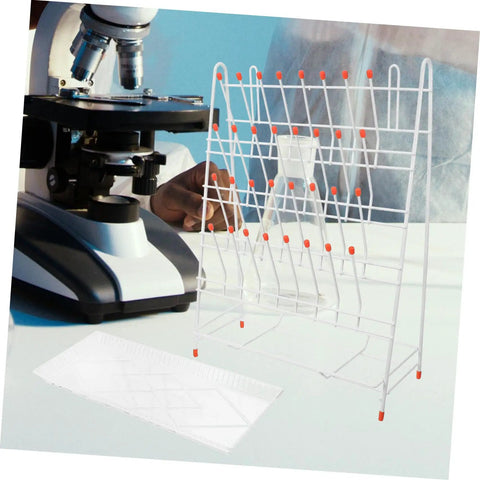 Built Tough White Metal Laboratory Bottle Drying Rack With Thirty Two Pegs For Test Tubes And Glassware beside a microscope.