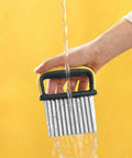 Front view of a two-piece stainless steel crinkle cutter with yellow and black handle being washed under running water