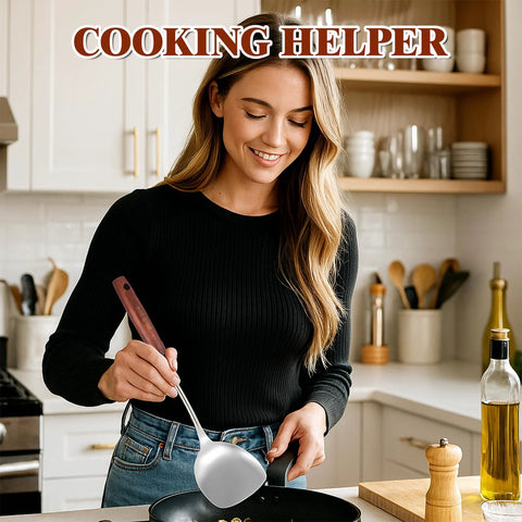 Side view of a silver stainless steel wok spatula with a wooden handle used to stir a pan.